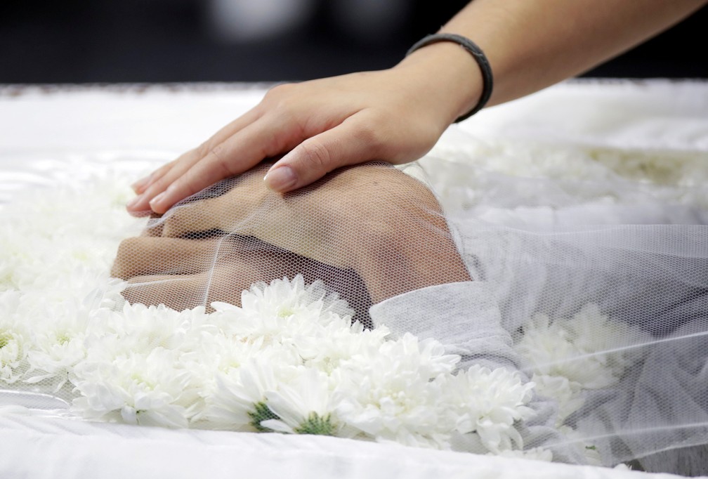 Uma pessoa toca as mãos de uma das vítimas do massacre na Escola Estadual Raul Brasil, em Suzano, durante velório nesta quinta-feira (14). Os corpos de seis vítimas foram velados no local — Foto: Ueslei Marcelino/Reuters